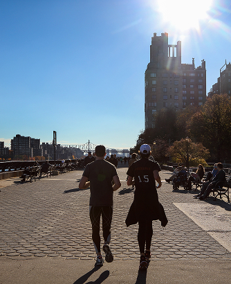Couple jogging on waterfront path in park near UES luxury apartments at 85 East End Ave, NYC.